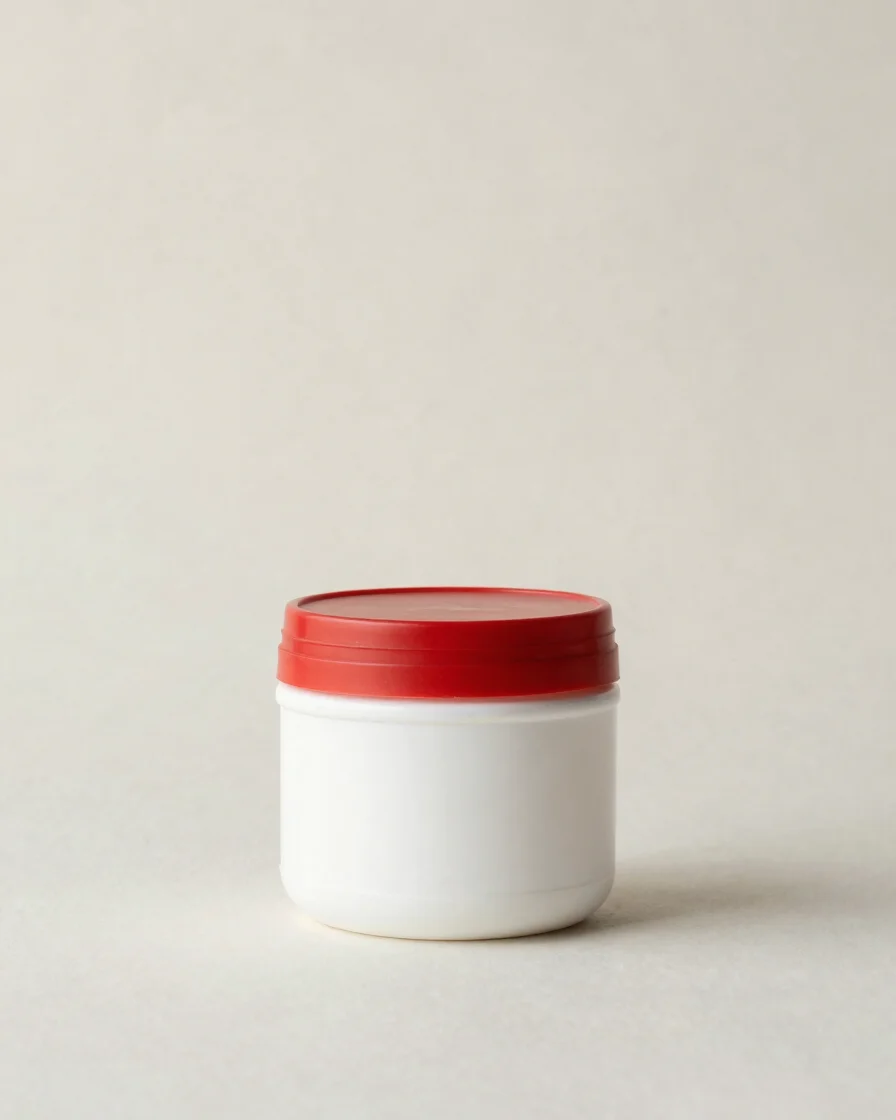 Clean editorial product photography, soft studio daylight, neutral crisp background, a single supplement container cente
